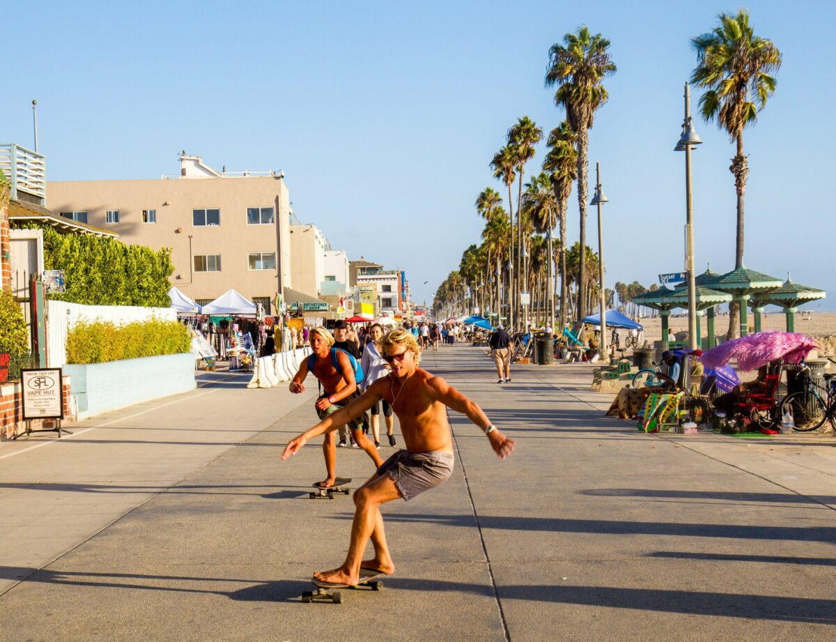 Skateboardings riding down Venice Beach Boardwalk on a nice day to demonstrate one of the best things to do in Los Angeles.