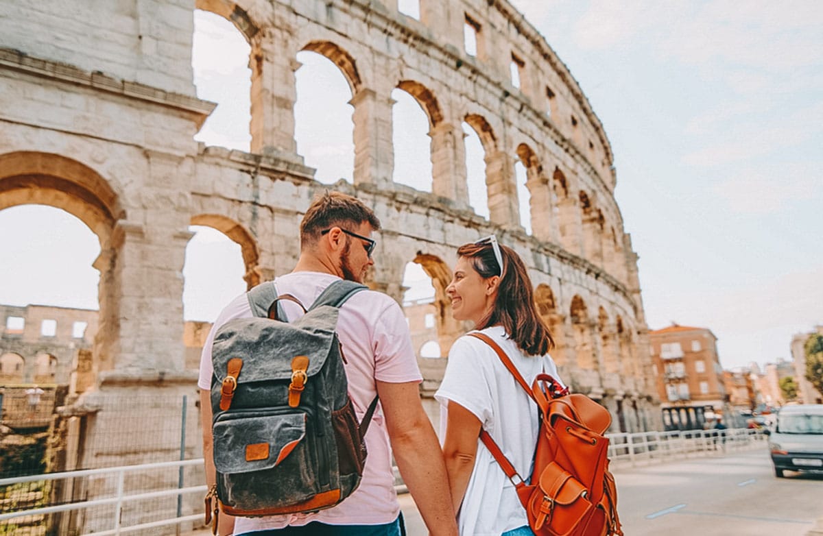 couple wearing backpacks near coliseum