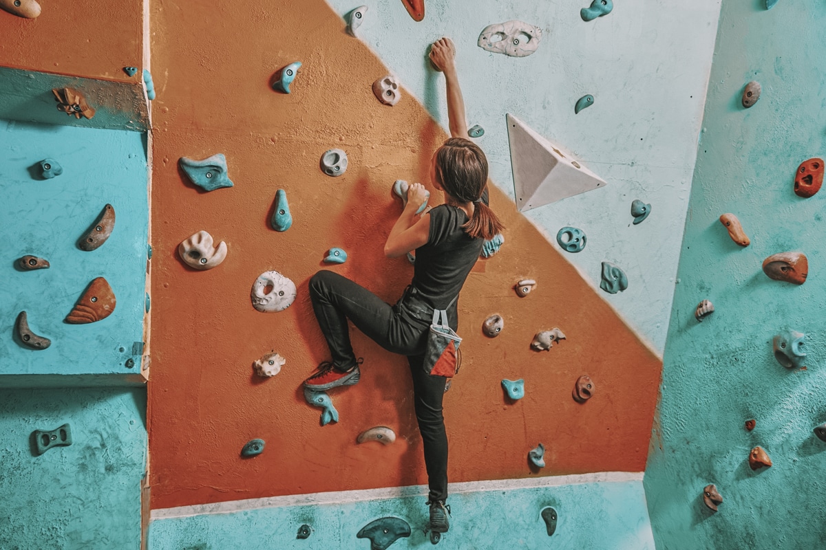 A woman climbing on a rock wall at a climbing gym.