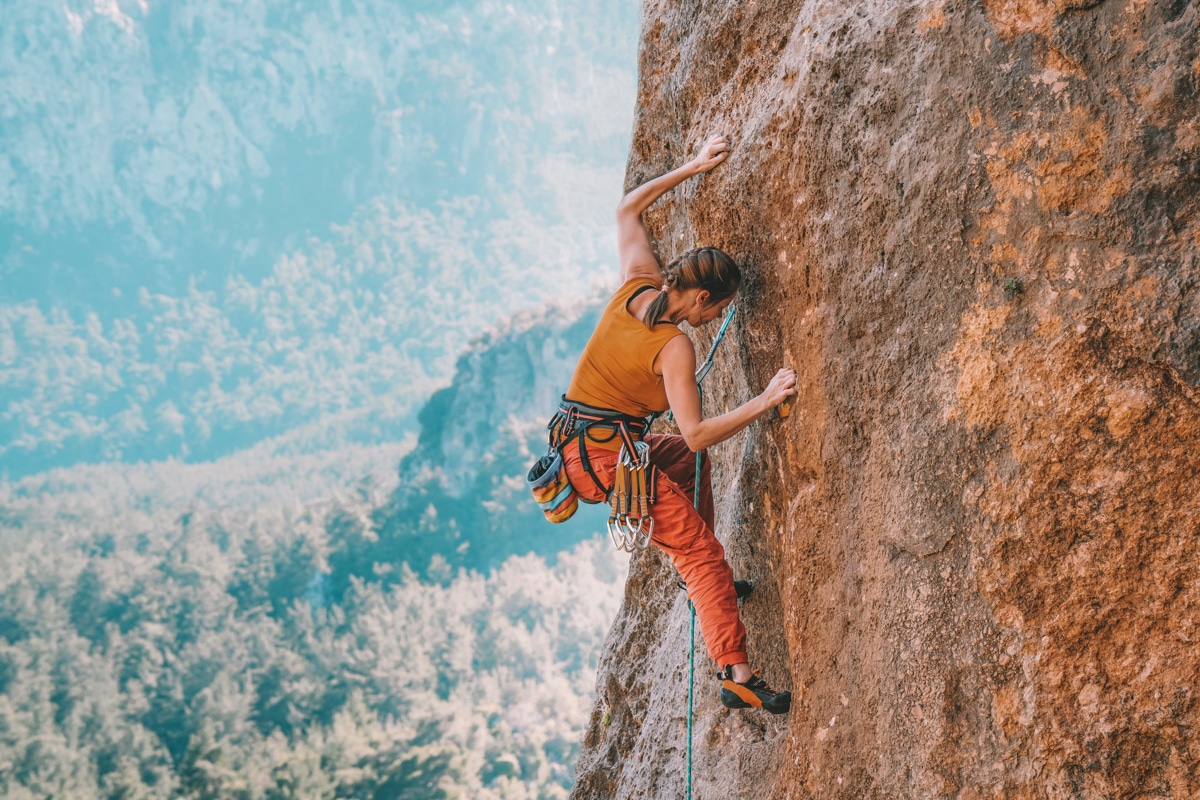 Image of a woman climbing a rock, gifts for rock climbers featured image