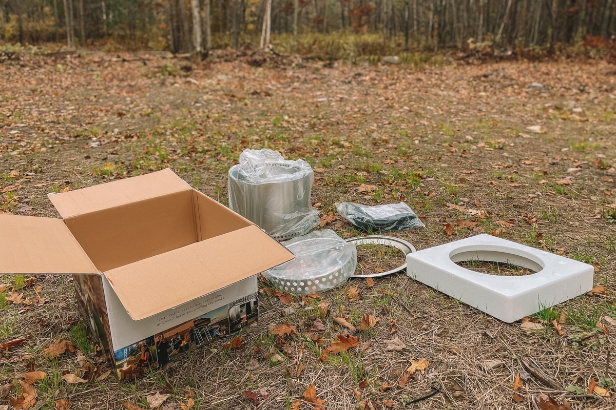 A brand new Solo Stove, unpacked, with it's box and packaging sitting on the ground outdoors.