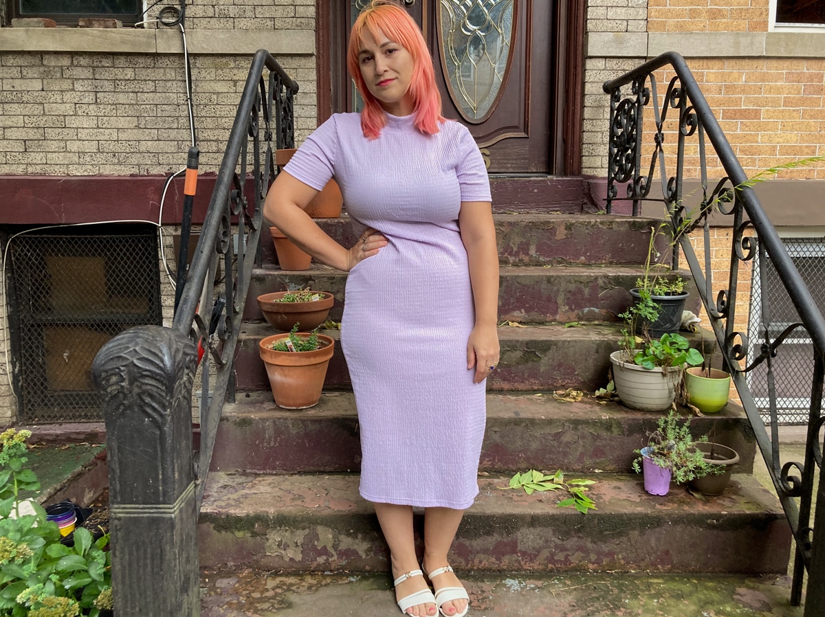 A woman wearing the Emery Rose mock neck bodycon dress in lavender